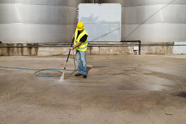 workman washing industrial site with pressure water